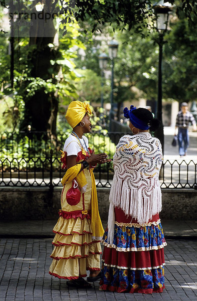 Zwei Kreolinnen in bunter Tracht unterhalten sich in einem Park  La Habana Vieja  Havanna  Kuba  Karibik