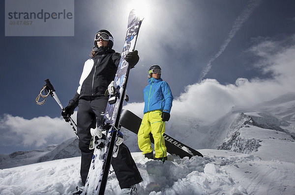 Snowboardfahrer und Snowboardfahrerin  stehend vor dramatischen Wolken  St. Moritz  Diavolezza  Schweiz  Europa