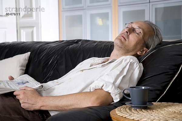 Mann auf Sofa mit Kaffeetasse ruht aus