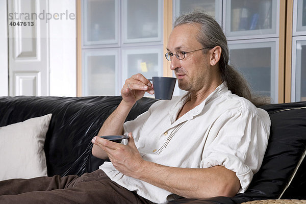 Mann trinkt auf Sofa gemütlich Kaffee