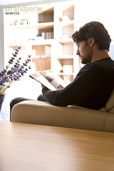 Mann sitzt gemütlich auf dem Sofa und liest