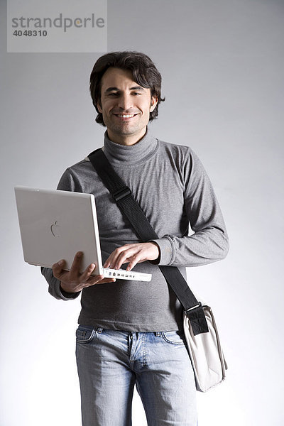 Junger Mann mit Laptop und Tasche