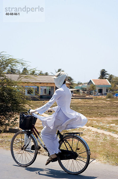 Frau auf Fahrrad mit der traditionellen vietnamesischen Tracht Ao Dai  Phan Thiet  Binh Thuan  Vietnam  Asien