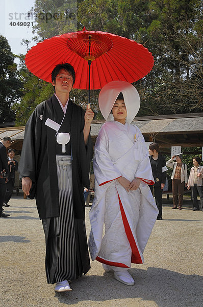 Traditionell gekleidetes japanisches Brautpaar mit Hochzeitskimonos  Frisurhaube und rotem Sonnenschirm vor dem Kamigamo Schrein in Kyoto  Japan  Asien