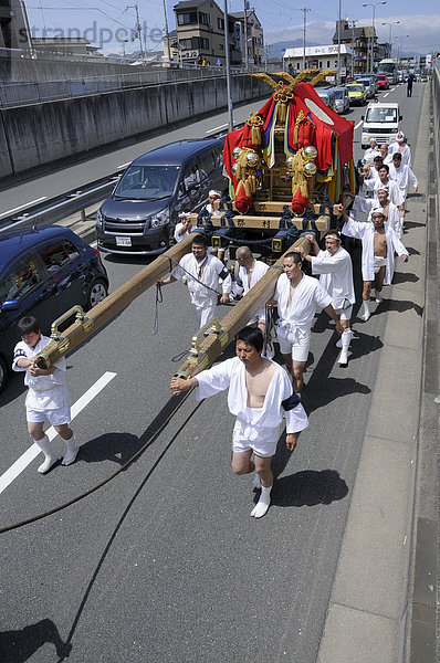 Prozession zieht im Straßenverkehr auf einer breiten Straße durch eine Unterführung  Schreinfest Matsuri des Matsuo Taisha Schreins  Shintoismus  Kyoto  Japan  Asien