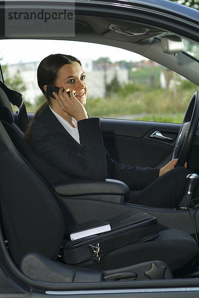 Junge Geschäftsfrau telefoniert im Auto