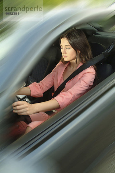 Junge Frau in einem rosa Anzug fällt in Sekundenschlaf am Steuer ihres Autos