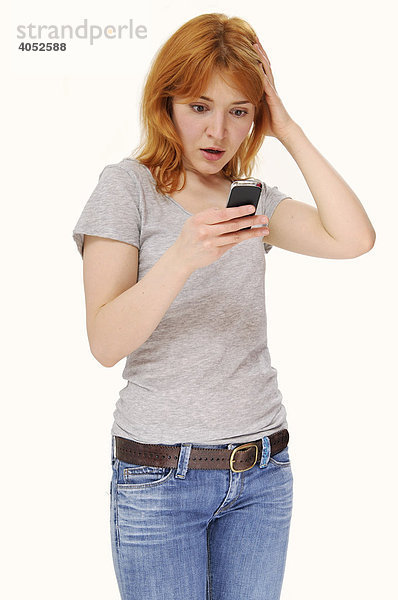 Rothaarige  attraktive Frau schreibt SMS mit Handy  überrascht  entsetzt