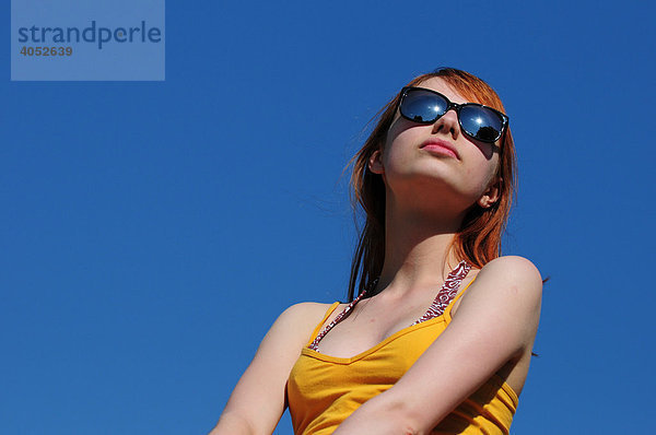 Rothaarige Frau mit gelbem Top  Sonnenbrille  attraktiv  schön  ernst  sonnt sich