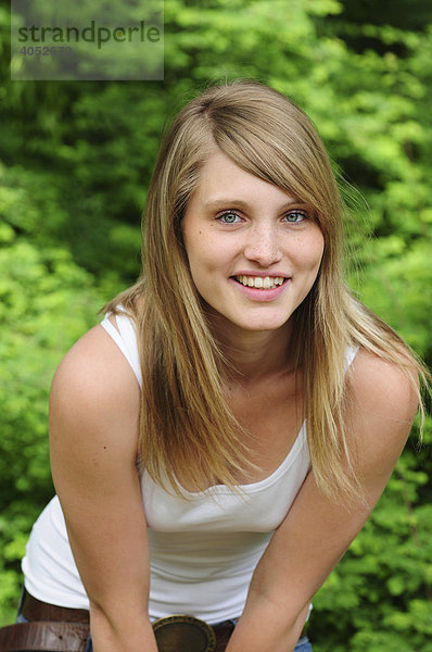 Portrait junge  schöne  blonde Frau im Sommer im Park  lächelt  lehnt sich nach vorne