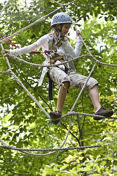 Junges Mädchen  ca. 11 Jahre  klettert an einem Netz zwischen zwei Bäumen  Kletterwald  Neroberg  Wiesbaden  Hessen  Deutschland  Europa