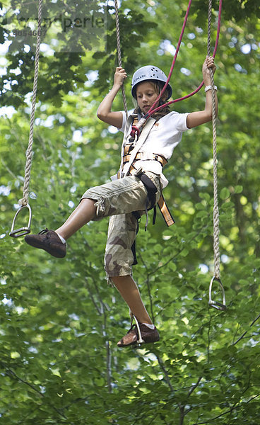 Junges Mädchen  ca. 11 Jahre  läuft auf Steigbügeln in ca. 10 Meter Höhe zwischen Bäumen  Kletterwald  Neroberg  Wiesbaden  Hessen  Deutschland  Europa