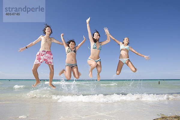 Kinder springen vor Freude am Meer in die Luft