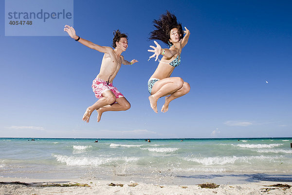 Kinder springen vor Freude am Meer in die Luft