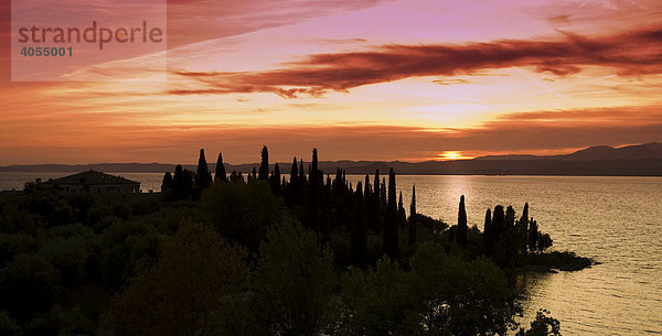 Eine alte Villa mit Zypressen am Ufer des Gardasees  Lago di Garda  im Sonnenuntergang bei der Ortschaft Lazise  Lombardei  Italien  Europa