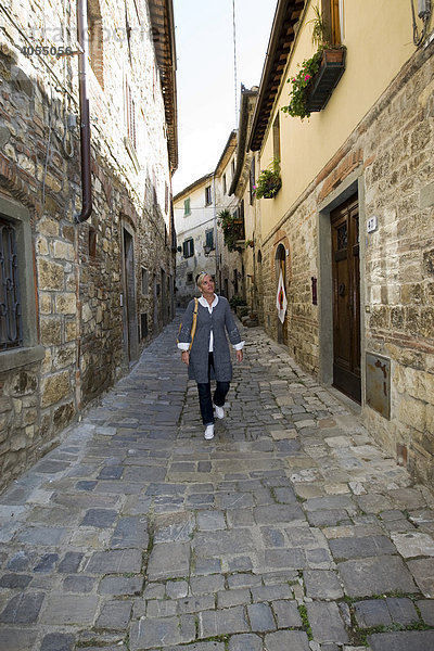 Ein Frau läuft durch ein typisches altes Weinstädtchen mit alten Gassen  Chianti  Provinz Florenz  Firenze  Toskana  Italien  Europa