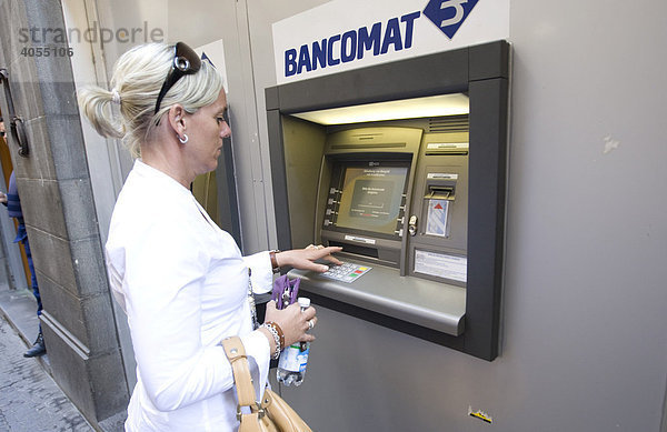 Frau zieht Bargeld an einem Geldautomaten in Siena  Siena  Toskana  Italien  Europa
