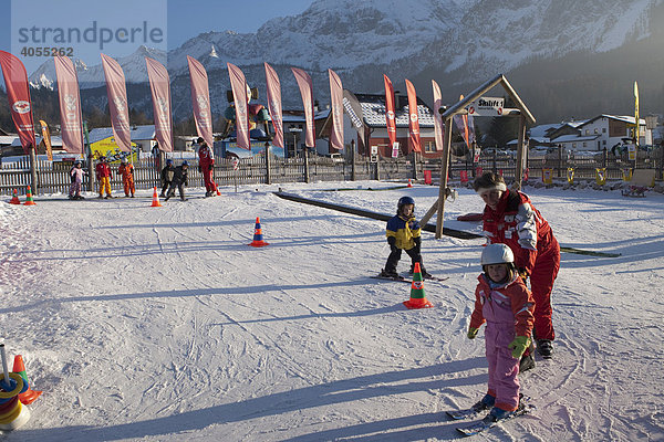 Kinder werden von einer Skilehrerin in einem Anfängerkurs in einer Skischule unterrichtet  hinten die Zugspitze  Ehrwald  Tirol  Österreich  Europa
