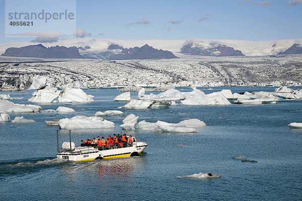 In der Gletscherlagune Jökulsarlon des Gletschers Vatnajökull kann man mit einem Landungsboot zwischen den schwimmenden Eisbergen  die zum Teil mit schwarzer Lava-Asche gefärbt sind  umherfahren  hinten die Gletscherzunge des Vatnajökull  Island  Europa