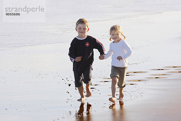 Junge  4 Jahre  und Mädchen  3 Jahre  springen und laufen Hand in Hand am Strand von Fuerteventura  Kanarische Insel  Spanien  Europa