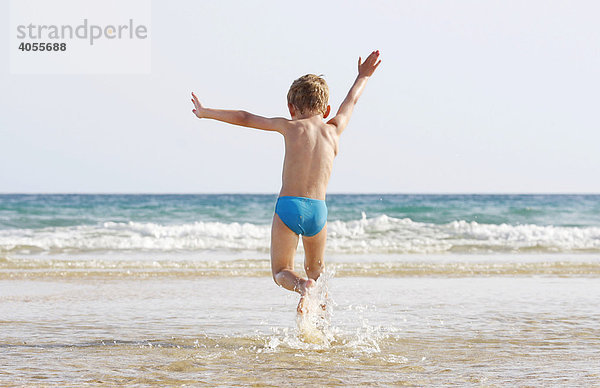 Junge  4 Jahre  springt und läuft voller Freude in den kleinen Wellen am Strand von Fuerteventura  Kanarische Insel  Spanien  Europa