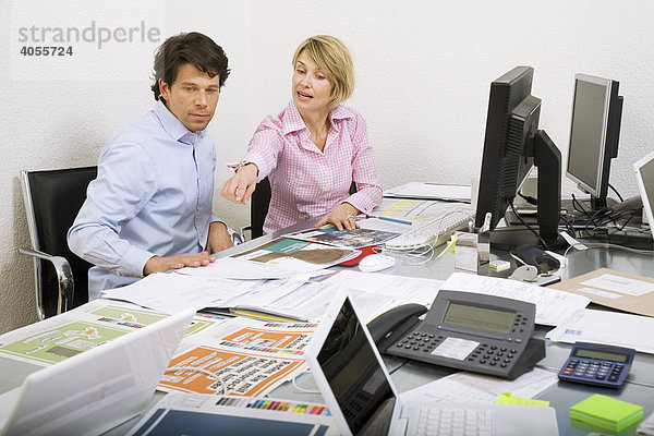 Mitarbeiterin und Mitarbeiter einer Werbeagentur beim Diskutieren einer Werbebroschüre und von Entwürfen für eine Werbekampagne  Zürich  Schweiz  Europa