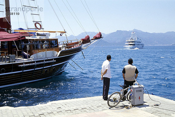 Zwei Männer blicken auf das Meer  Boote im Hafen  Marmaris in der Provinz Mugla  Mittelmeer  Türkei