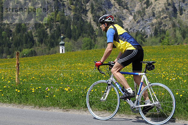 Rennradfahrer  Kirchturm von Kössen  Tirol  Österreich  Europa