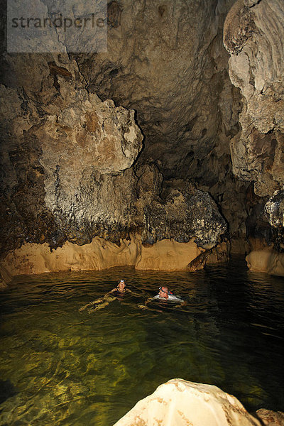 Mann und Frau mit LED Kopflampen erkunden schwimmend Höhle mit warmem Wasser  Punta Gorda  Belize  Zentralamerika  Karibik