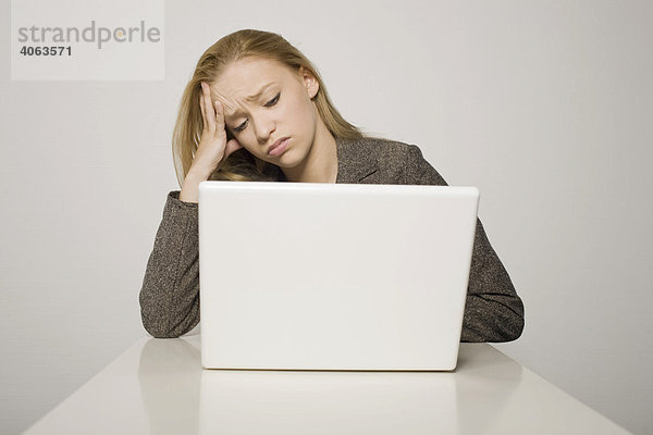 Junge langhaarige Frau sitzt verzweifelt vor ihrem Computer  Notebook