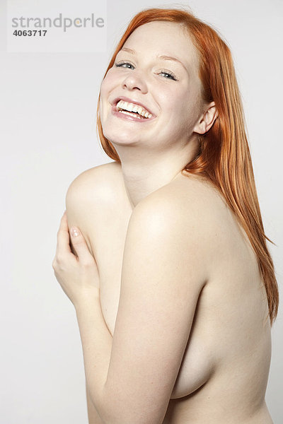 Junge rothaarige Frau mit unbekleidetem Oberkörper vor Weiß