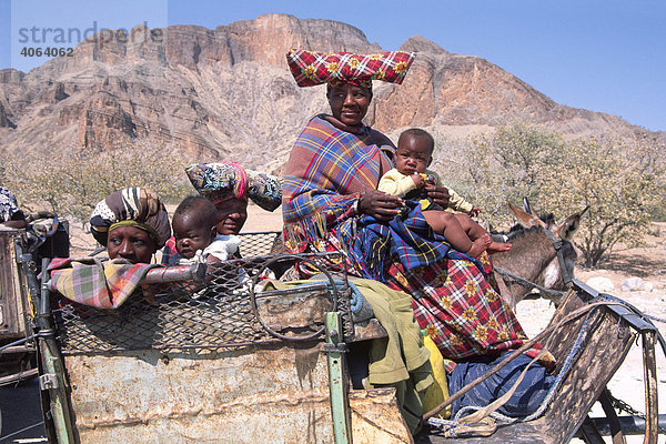Hererofrauen in typischer Tracht mit Babys auf Eselskarren  Sesfontein  Kaokoveld  Namibia  Afrika