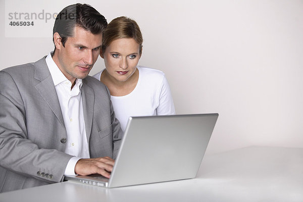 Frau mit ernstem Blick und Mann am Laptop