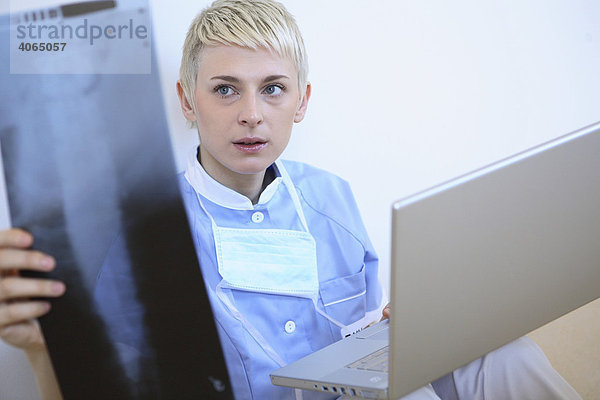 Überarbeitete Krankenschwester mit Laptop und Röntgenfilm