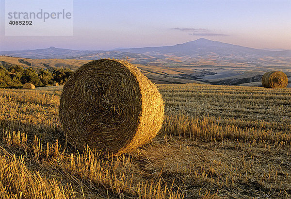 Strohballen  abgeerntete Weizenfelder  Landschaft vor Radicofani und Monte Amiata bei Sonnenuntergang  Val d' Orcia bei Monticchiello  Provinz Siena und Grosseto  Toskana  Italien  Europa
