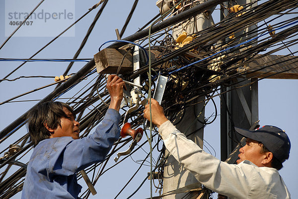 Elektrifizierung ohne Arbeitsschutz  Elektriker arbeiten im Gewirr von Stromkabeln  Vientiane  Laos  Asien