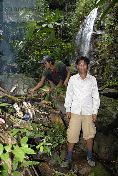 Laoten grillen Fisch im Dschungel bei einem Wasserfall  Phongsali Provinz  Laos  Südostasien