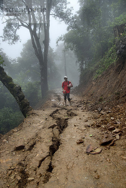 Erdrutschgefahr junger Mann steht vor Spalte im Weg als Vorbote von einem drohenden Erdrutsch  Nebelwald bei Ban Saenlouang  Phongsali Provinz  Laos  Südostasien