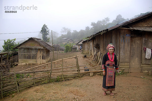 Junge Frau der Akha Pala Ethnie gekleidet in traditionelle bunte Tracht steht im Dorf  Ban Saenkham Tai  Phongsali Provinz  Laos  Südostasien