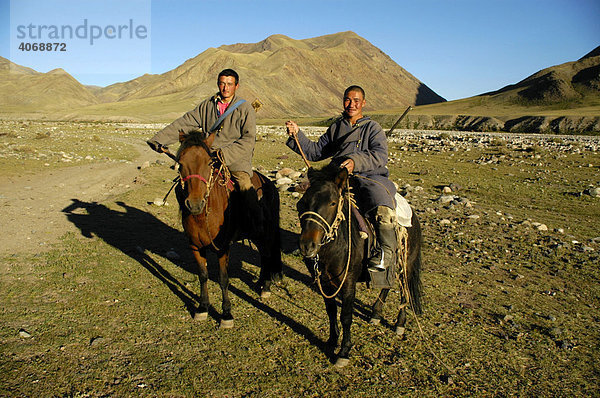 Nomaden  zwei junge Männer in traditioneller Kleidung mit Gewehren sitzen auf ihren Pferden in der Steppe  Kharkhiraa  Mongolischer Altai bei Ulaangom  Uvs Aimag  Mongolei  Asien