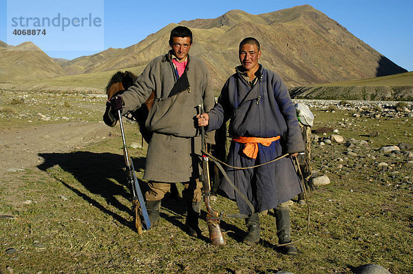 Nomaden  junge Männer in traditioneller Kleidung mit Gewehr stehen in der Steppe  Kharkhiraa  Mongolischer Altai bei Ulaangom  Uvs Aimag  Mongolei  Asien