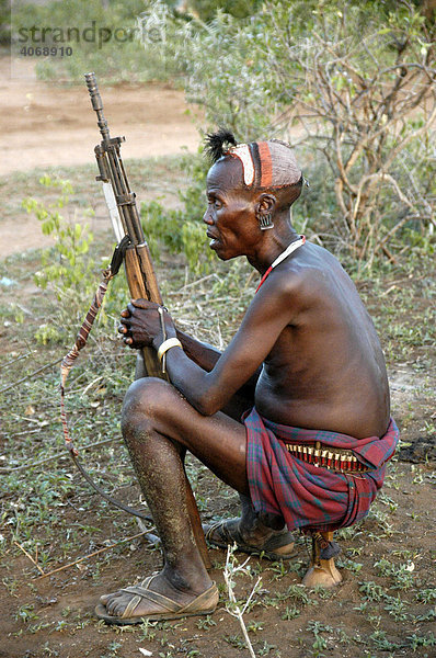 Mann mit Gewehr sitzt und schaut  Volk der Hamar  Turmi  Äthiopien  Afrika
