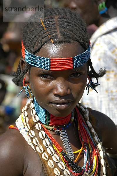 Portrait  Mädchen mit buntem Kopfschmuck und Kaurimuscheln als Halskette  Markt von Dimeka  Äthiopien  Afrika