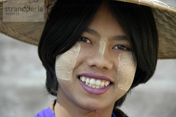 Lächelnde junge Frau mit Tanaka im Gesicht und Reishut auf dem Kopf  Mingun  bei Mandalay  Birma  Burma  Myanmar  Südostasien