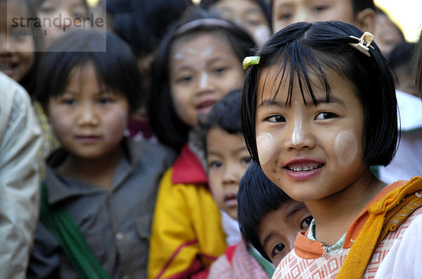 Lächelndes Mädchen mit Tanaka im Gesicht in einer Gruppe Kinder  Birma  Burma  Myanmar  Südostasien