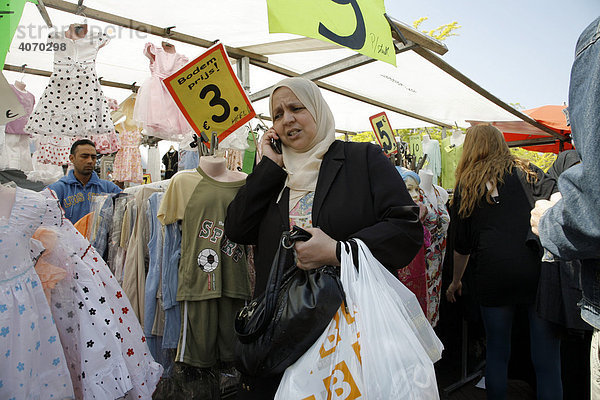 Frau mit Kopftuch telefoniert  Kleiderstand Dappermarkt  multikultureller Straßenmarkt  Basar  Dapperstraat  Amsterdam  Niederlande  Europa