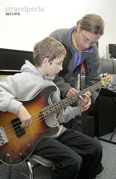 Ein 15-jähriger Jugendlicher beim Musikunterricht mit einer E-Bassgitarre mit seinem Musiklehrer in der privaten Musikschule Music Academy in Regensburg  Bayern  Deutschland  Europa