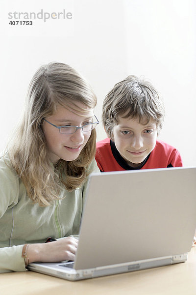 Ein Mädchen  13 Jahre alt  und ihr Bruder  10 Jahre alt  sitzen vor einem Laptop