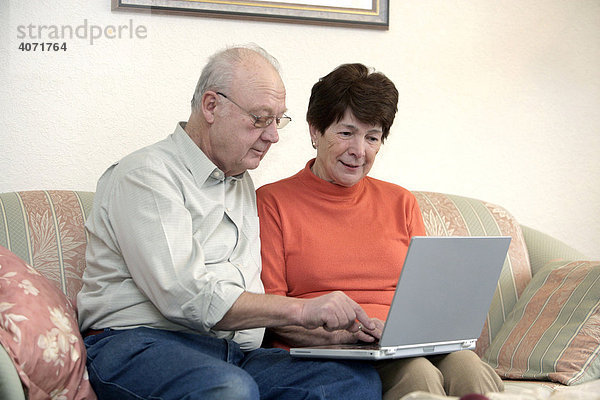 Seniorenpaar sitzt zusammen vor einem Laptop