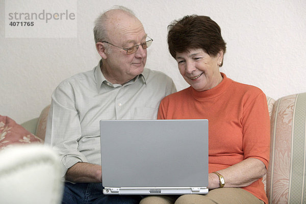 Seniorenpaar sitzt zusammen vor einem Laptop